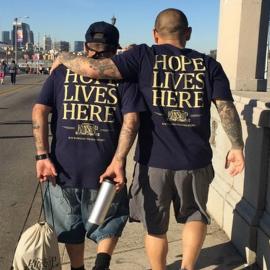 Two men walking with matching shirt that say Home Lives Here